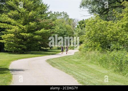 Aurora, Illinois, Stati Uniti-Aprile 19,2014: Due donne che camminano sul percorso insieme alla crescita della prateria e varietà di alberi ad Aurora, Illinois Foto Stock