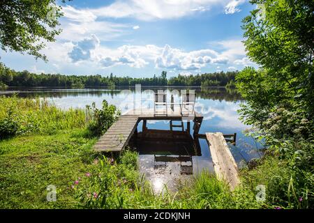 splendido paesaggio estivo con sedie in legno sul ponte pedonale del lago Foto Stock