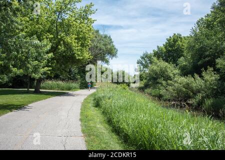 Aurora, Illinois, Stati Uniti-Aprile 19,2014: Una persona che corre sul sentiero da sola il Waubonsie Creek Trail ad Aurora, Illinois Foto Stock