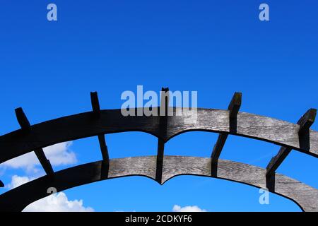 Arco di giardino in legno dipinto di nero, a metà del sole in ombra, contro un cielo blu chiaro ai giardini ornamentali, Ottawa, Ontario, Canada. Foto Stock