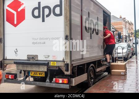 Un conducente di consegna DPD scarica alcune scatole di cartone per consegnarlo al cliente. Foto Stock