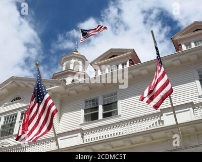 Tre bandiere statunitensi sfogano dal piano superiore ornato dello storico Stanley Hotel di Estes Park, Colon. Foto Stock