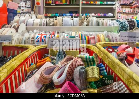 Fasci e bobine di nastri di tessuto colorato per la vendita in un negozio Foto Stock