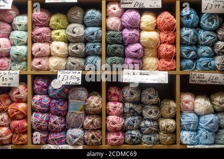 Palle di lana di maglia colorata disposte su scaffale in vendita in un negozio. Foto Stock