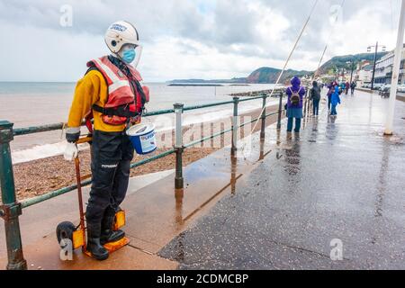 Un manichino vestito con attrezzatura di sicurezza per imbarcazioni di salvataggio RNLI, fissato a un carrello manuale, viene sostenuto contro le ringhiere per raccogliere donazioni a Sidmouth, Regno Unito Foto Stock