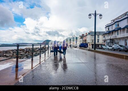 Una passeggiata in famiglia lungo la spianata sul lungomare di Sidmouth, South Devon, Regno Unito, in una giornata bagnata. Foto Stock