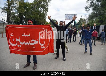 I lutto di Kashmiri shia detengono la bandiera mentre gridano gli slogan religiosi durante la processione di muharram. Le autorità hanno imposto severe restrizioni in molte aree di Srinagar per vietare la processione dell'8° Muharram. Foto Stock