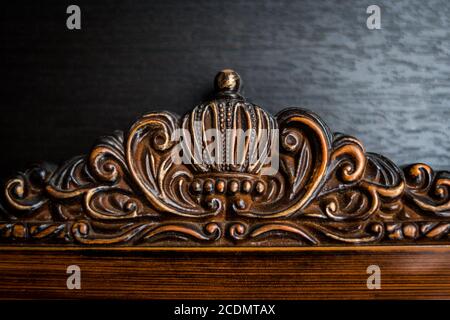 Cornice in legno con corona intagliata su una superficie nera Foto Stock