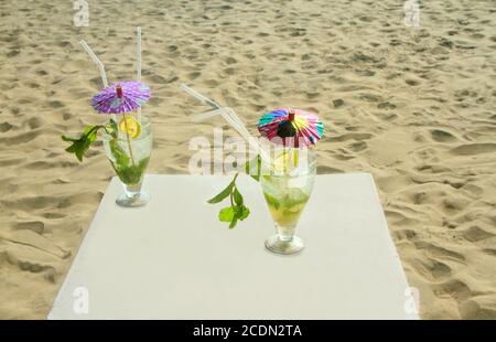 cocktail mojito con ghiaccio, rum, lime e menta in un bicchiere sulla spiaggia di sabbia Foto Stock