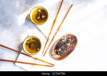 Concetto di bevande a base di tè in stile asiatico con tazze da tè e. bastoncini di pollo su sfondo bianco in cemento con spazio per la copia Foto Stock