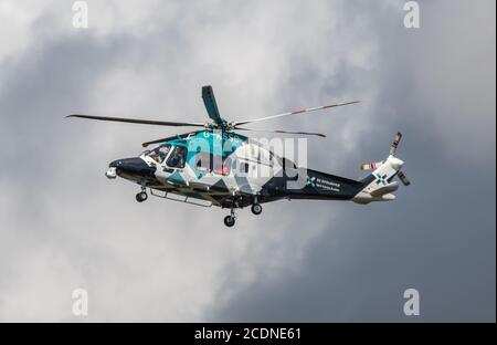 Helimed Air Ambulance per Kent, Surrey & Sussex, un elicottero medico, G-KSSC, AgustaWestland AW169, che vola in cielo tempestoso grigio nel Regno Unito. Foto Stock