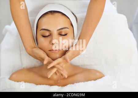 Massaggio viso. L'estetista effettua un massaggio viso anti-invecchiamento con le mani in una clinica di cosmetologia Foto Stock