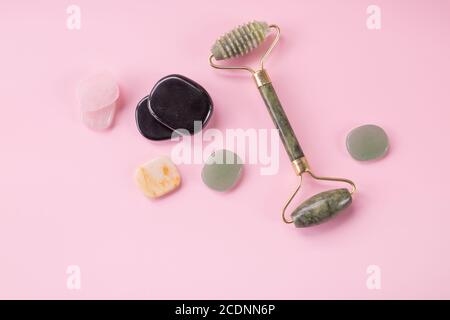 rulli di massaggio viso su sfondo rosa. Concetto di cura di sé e di bellezza. Copia spazio. Jade Face Roller e Gua sha Stone per un massaggio viso di bellezza Foto Stock