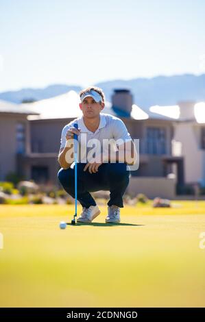 metà anni venti golfer maschio che pianifica la sua messa ha sparato al puntate su un verde in una giornata di sole Foto Stock