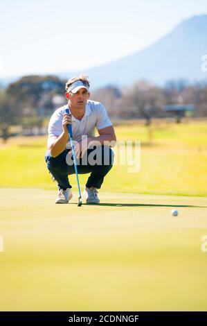 metà anni venti golfer maschio che pianifica la sua messa ha sparato al puntate su un verde in una giornata di sole Foto Stock