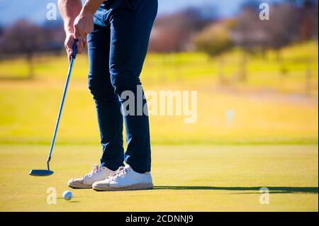 metà anni venti golfer maschio che pianifica la sua messa ha sparato al puntate su un verde in una giornata di sole Foto Stock