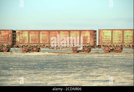 Vecchio treno arrugginito vetture con stalattiti di sale nel lago Baskunchak Foto Stock