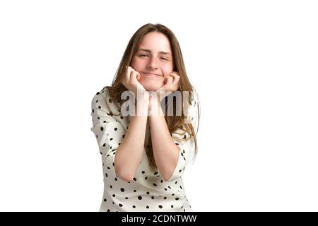 Una giovane donna dai lunghi capelli marroni e da un abito bianco a pois di polka, appoggia il mento sulle mani Foto Stock