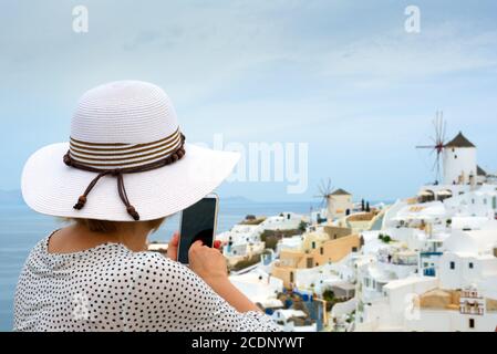 Donna che scatta foto mobile del villaggio bianco in Grecia Foto Stock