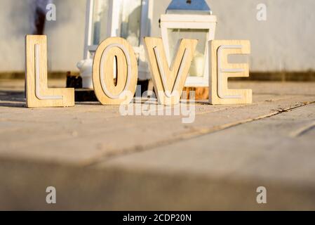 Lettere di legno che formano la parola AMORE sulla terra all'aperto in un evento. Foto Stock