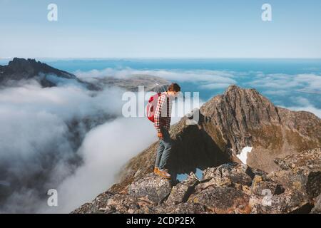 Uomo avventuriero escursioni in montagna con zaino viaggio trekking all'aperto Sole vacanze estive attività sano stile di vita percorso in Norvegia sopra cloud Foto Stock