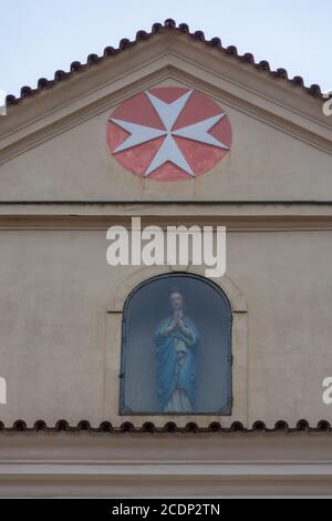 Croce di Malta, simbolo dell'ordine medievale di San Giovanni, sopra una statua di una Vergine Maria in preghiera Foto Stock