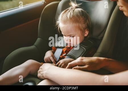 Bambina in seggiolino per auto di sicurezza e cintura di sicurezza per la madre viaggio in famiglia vacanza stile di vita con il trasporto di sicurezza del bambino Foto Stock