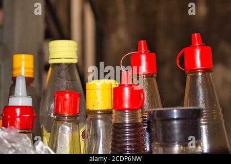 Bottiglie di salsa di plastica con tappi colorati Foto Stock