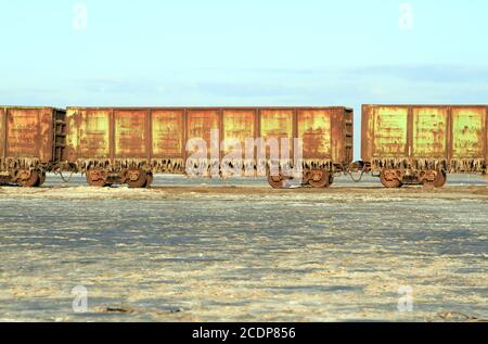 Vecchio treno arrugginito vetture con stalattiti di sale nel lago Baskunchak Foto Stock