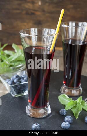 Bicchieri con succo di ribes nero fresco. Bog mirtillo e balsamo di limone Foto Stock