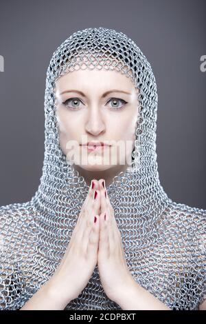 Giovane donna con cappuccio medievale di Chainmail con le mani piegate Foto Stock