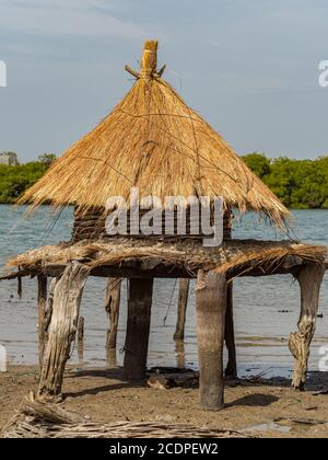 Piccolo granaio con un tetto spiovente su un'isola tra alberi di mangrovie, Joal-Fadiouth, Senegal Africa Foto Stock