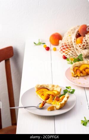 Delizioso pezzo di torta di pasta frolla con pesca su un piatto con forchetta, cotto nel forno clafoutis di pesca Foto Stock