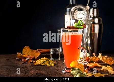 Rum caldo al burro, cocktail alcolico caldo autunno o inverno con succo di mela e limone, rum scuro, miele, cannella in calice alto su fondo scuro Foto Stock