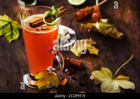 Rum caldo al burro, cocktail alcolico caldo autunno o inverno con succo di mela e limone, rum scuro, miele, cannella in calice alto su fondo scuro Foto Stock