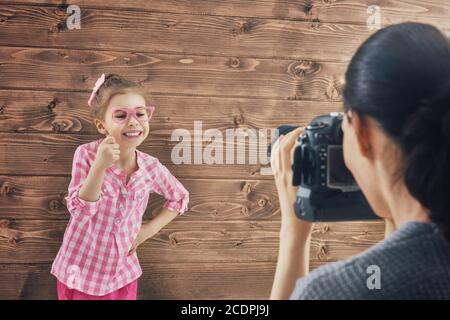 Fotografo in movimento. Giovane fotografo donna e bambina che si diverte alla sessione fotografica. Foto Stock