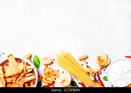 Ingredienti per cucinare la pasta con i finferli di funghi in una salsa cremosa, sfondo del cibo, vista dall'alto Foto Stock