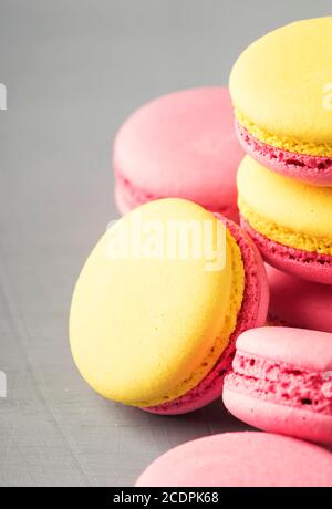 Macaroon giallo rosa torte su sfondo grigio tavolo, posto per il testo, stile minimalismo alla moda, fuoco selettivo Foto Stock
