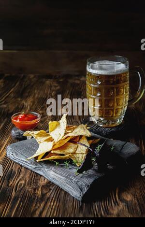 nachos su sfondo di legno con una tazza di birra. Copia dello spazio Foto Stock