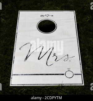 Un gioco di wite cornhole su un prato verde con MRS scritto in nero. Foto Stock