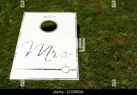 Un gioco di cornhole bianco su un prato verde con MRS scritto in nero come regalo di nozze. Foto Stock