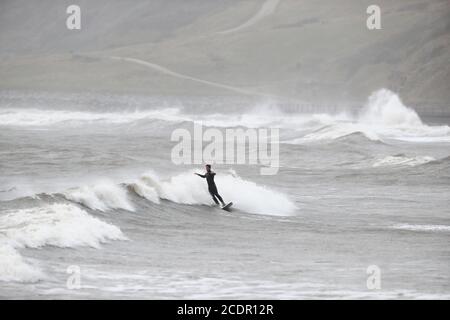 Un surfista ama le acque aspro di Scarborough, nello Yorkshire settentrionale. Data immagine: Sabato 29 agosto 2020. I previsori prevedono che questo lunedì di festa della Banca potrebbe essere il più freddo mai registrato per alcune parti del Regno Unito, poiché si prevede che le temperature siano ben al di sotto della media per il periodo dell'anno. Guarda la storia di PA tempeste DI TEMPO. Il credito fotografico dovrebbe essere: Danny Lawson/PA Wire Foto Stock