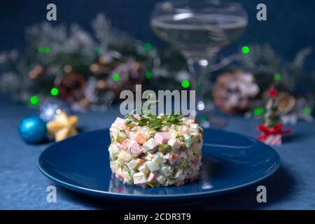 Insalata Olivier su piatto blu, decorata con germogli di piselli. Tradizionale insalata russa di Capodanno e Natale. Foto Stock