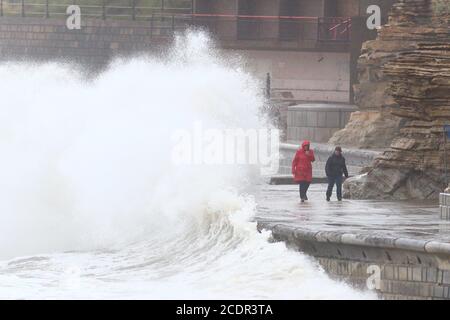 Persone che camminano lungo il ventoso lungomare di Scarborough, North Yorkshire. Data immagine: Sabato 29 agosto 2020. I previsori prevedono che questo lunedì di festa della Banca potrebbe essere il più freddo mai registrato per alcune parti del Regno Unito, poiché si prevede che le temperature siano ben al di sotto della media per il periodo dell'anno. Guarda la storia di PA tempeste DI TEMPO. Il credito fotografico dovrebbe essere: Danny Lawson/PA Wire Foto Stock