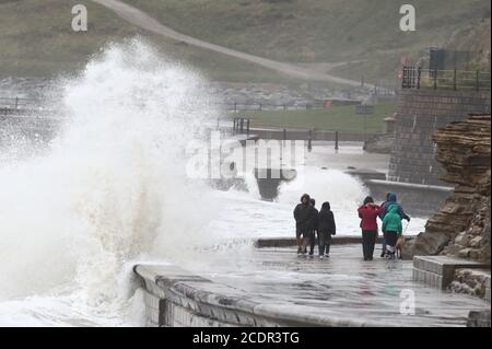 Persone che camminano lungo il ventoso lungomare di Scarborough, North Yorkshire. Data immagine: Sabato 29 agosto 2020. I previsori prevedono che questo lunedì di festa della Banca potrebbe essere il più freddo mai registrato per alcune parti del Regno Unito, poiché si prevede che le temperature siano ben al di sotto della media per il periodo dell'anno. Guarda la storia di PA tempeste DI TEMPO. Il credito fotografico dovrebbe essere: Danny Lawson/PA Wire Foto Stock