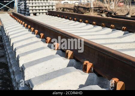 Nuove rotaie e traversine. Le rotaie e le traversine sono impilate l'una sull'altra. Ristrutturazione della ferrovia. Ferrovia per il treno Foto Stock