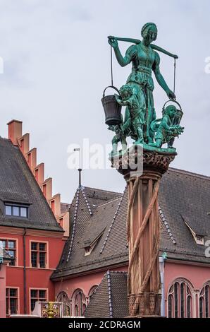 Scena con una donna che porta acqua sulla fontana di Raubrunnen nel centro storico di Friburgo in Breisgau, Baden-Wurttemberg, Germania. Foto Stock