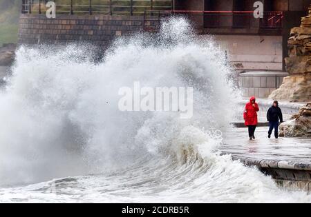 Persone che camminano lungo il ventoso lungomare di Scarborough, North Yorkshire. Data immagine: Sabato 29 agosto 2020. I previsori prevedono che questo lunedì di festa della Banca potrebbe essere il più freddo mai registrato per alcune parti del Regno Unito, poiché si prevede che le temperature siano ben al di sotto della media per il periodo dell'anno. Guarda la storia di PA tempeste DI TEMPO. Il credito fotografico dovrebbe essere: Danny Lawson/PA Wire Foto Stock