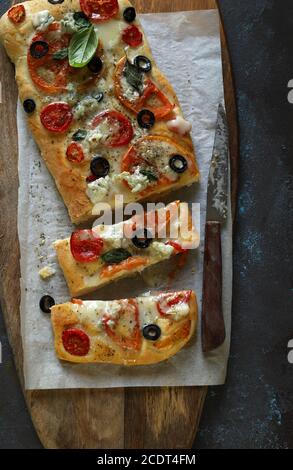 Pizza fatta in casa con verdure fresche, formaggio e foglie di basilico. Vista dall'alto. Concetto di cibo italiano. Foto Stock