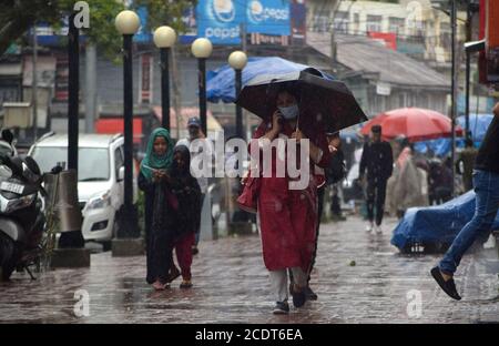 Persone che camminano durante forti piogge a Srinagar, India. Foto Stock